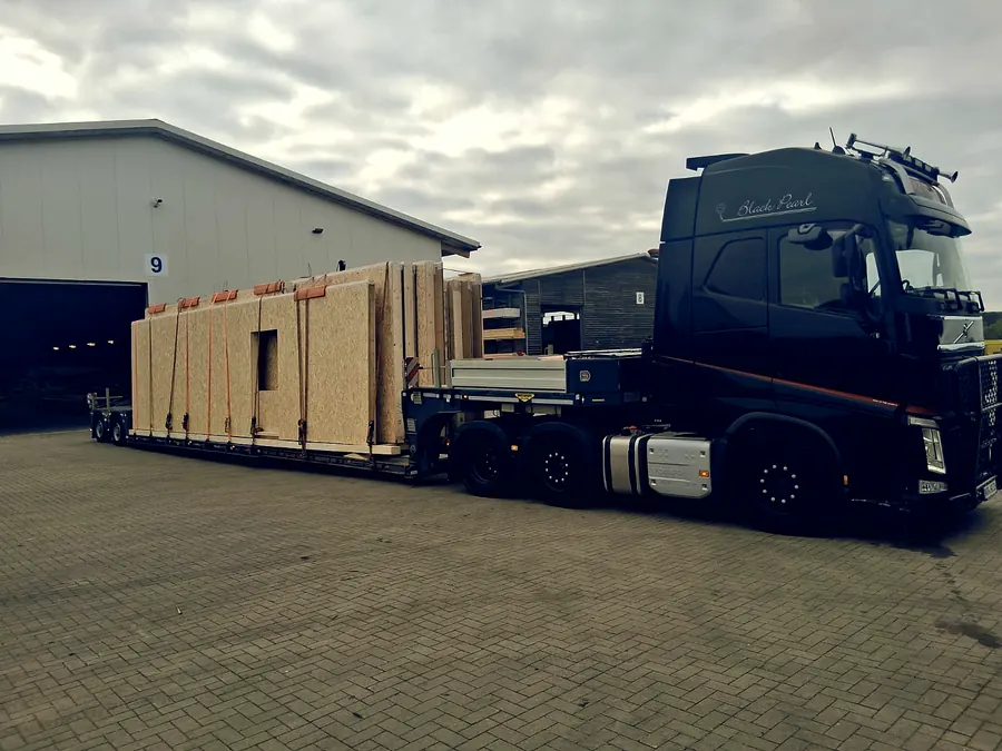 Black Pearl Volvo FH mit Holz-Wandelementen vor der Halle
